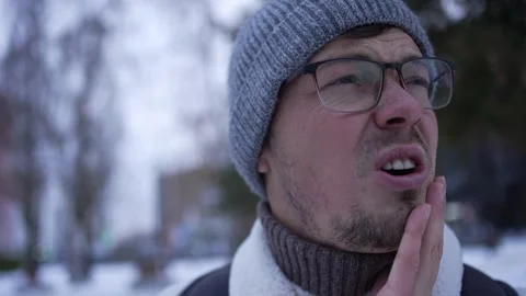 Man experiencing intense tooth pain outdoors in winter Stock Footage 293477980