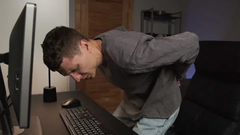Man experiencing lower back pain at desk during work from home, authentic home Stock Footage 316372684