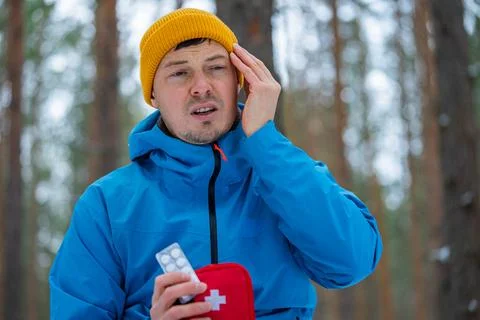 Man experiencing severe headache or migraine during a winter hike, holding Stock Photos