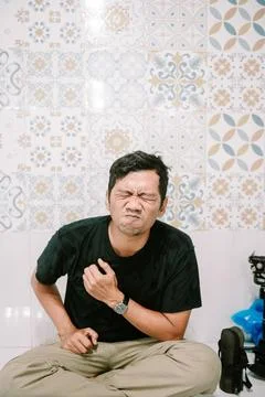 Man experiencing sharp chest pain against decorated tile background Stock Photos