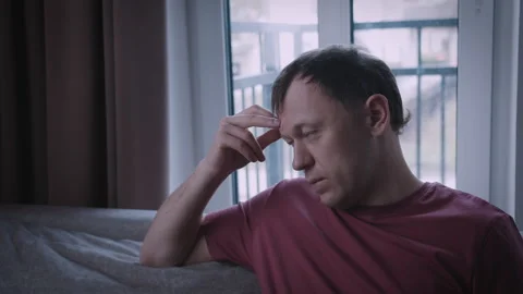 A man is experiencing stress, his face serious and upset, the man is sitting on Stock Footage 318302937