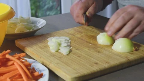 Man expertly cuts onions for a fresh salad preparation in a cozy kitchen se.. Stock Footage 310714670