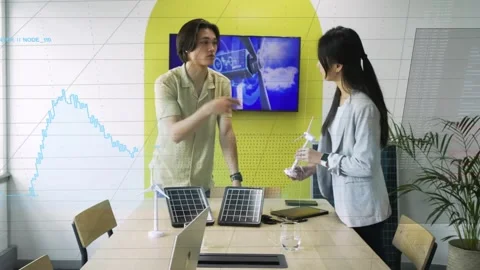 Man explaining energy prototype urging woman picking turbine and aligning solar Stock Footage 331002544