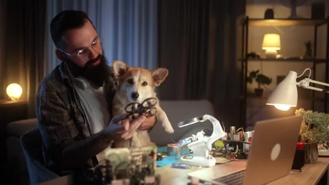 Man explaining his drone build to a corgi in a home workshop Stock Footage 304618399