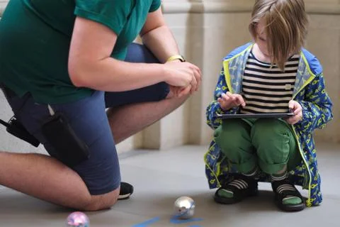 A man explains to a boy the rules of a game with robots controlled from a tab Stock Photos