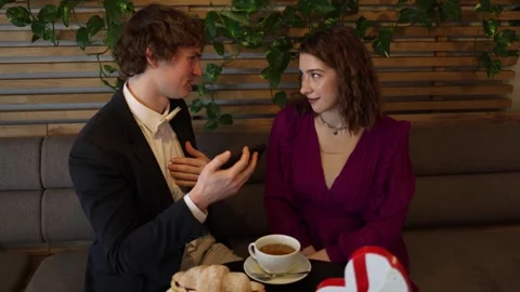 Man explains something on phone during date Stock Footage 328145851