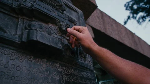 Man explores ancient temple carvings at historic site during sunset Stock Footage 321435205