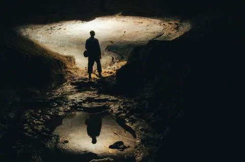 Man exploring dark cave underground tunnel Stock Photos