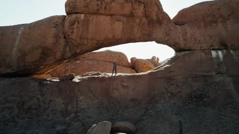Man Exploring Natural Rock Arch in African Desert Stock Footage 301369206