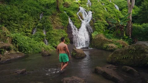 Man Exploring Pelisan Waterfall, Walking Multi-Tiered Rocky River in Bali Stockbeeldmateriaal 347789230