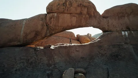 Man Exploring Rock Arch in African Desert Stock Footage 301368606