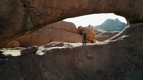 Man Exploring Rock Arch in African Desert Stock Footage 301369004