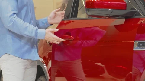 Man exploring a sleek new automobile at a vibrant car dealership Stock Footage 311945907