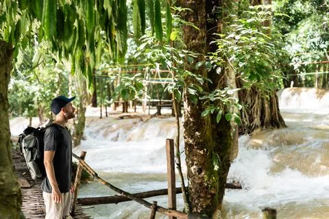 Man exploring tropical waterfall cascades in jungle during travel 写真素材