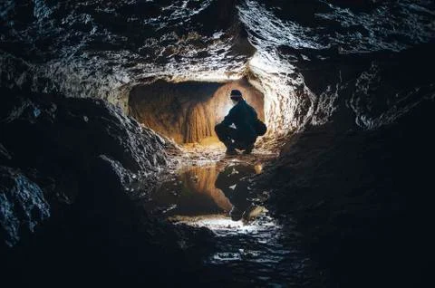 Man exploring underground cave Stock Photos