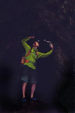 Man exploring underground dark cave Stock Photos
