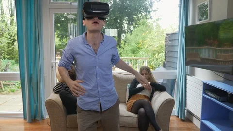 Man exploring VR world with bored friends behind him Stock Footage 89921167