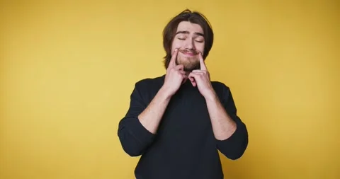 Man expresses different moods using facial gestures in a studio with a yell.. 動画素材 328249949