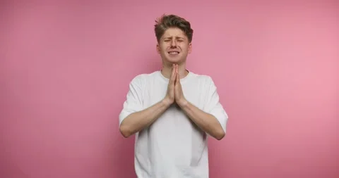 Man expresses emotions using hand gestures against a pink background in fou.. Stockbeeldmateriaal 328246960