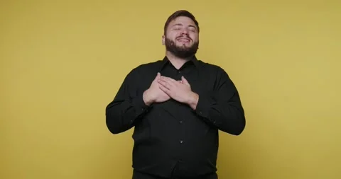Man expresses gratitude with sign language in front of a yellow background .. 動画素材 326798936