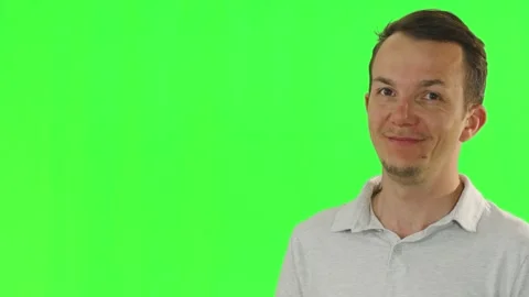 Man expressing amusement and smiling at someone off-camera on green screen Stock Footage 309798792