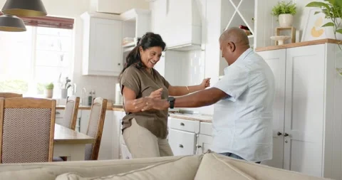 Man extending arms starting dance in bright kitchen as couple mirroring steps, Stock Footage 342930079