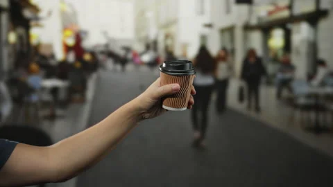 Man extends arm with coffee cup on a bustling city street, showcasing urban.. Stock Footage 303027207
