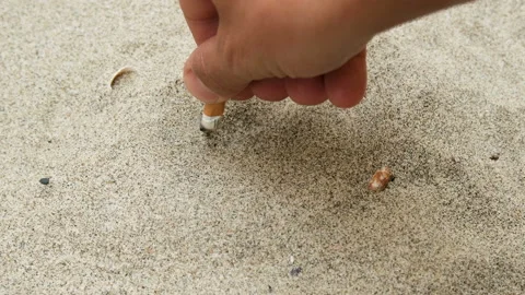Man extinguish cigarette butt on sandy sea ecosystem,ocean trash pollution Stock Footage 133242918