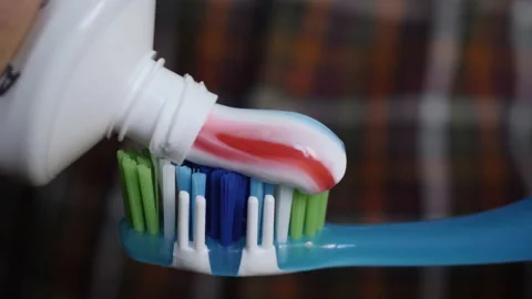 Man Extruded Toothbrush With Bright Striped Toothpaste. Macro Shot Red and Bl Stock Footage 154886700