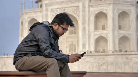 A man in eye glasses sitting in front of the taj Mahal Stock Footage 139886801