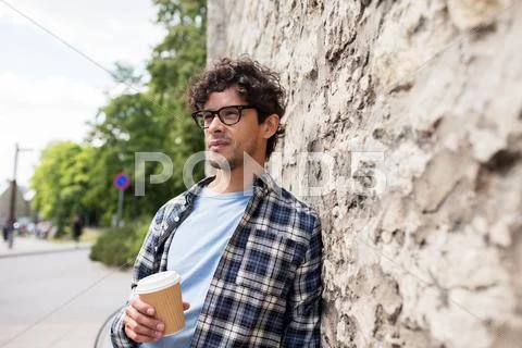 Man in eyeglasses drinking coffee over street wall Stock Photos