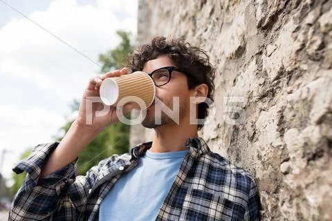 Man in eyeglasses drinking coffee over street wall Stock Photos