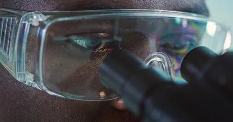 Man in eyeglasses is looking through a microscope Stock Photos