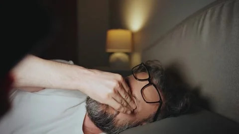 A man in eyeglasses lying in bed using smartphone late at night. 스톡 동영상 342955150