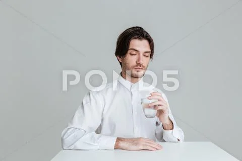 Man with eyes closed drinking from water glass at table Stock Photos