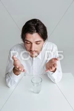 Man with eyes closed making hand gestures at the table Stock Photos
