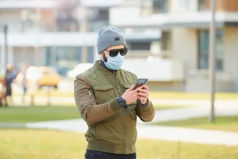 A man in a face mask to avoid the spread coronavirus holding a smartphone Stock Photos