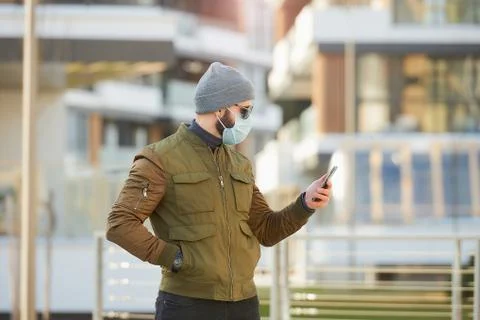 A man in a face mask to avoid the spread coronavirus holding a smartphone Stock Photos