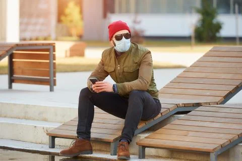 A man in a face mask to avoid the spread coronavirus holding a smartphone Stock Photos