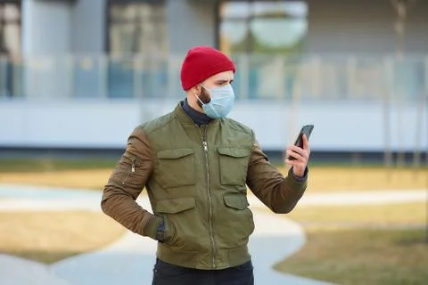 A man in a face mask to avoid the spread coronavirus holding a smartphone Stock Photos