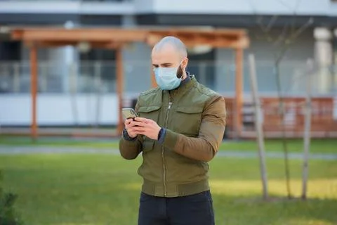A man in a face mask to avoid the spread coronavirus holding a smartphone Stock Photos