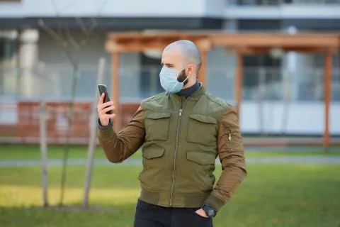 A man in a face mask to avoid the spread coronavirus holding a smartphone Stock Photos