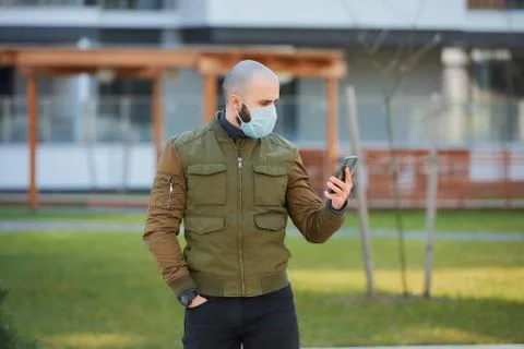 A man in a face mask to avoid the spread coronavirus holding a smartphone Stock Photos