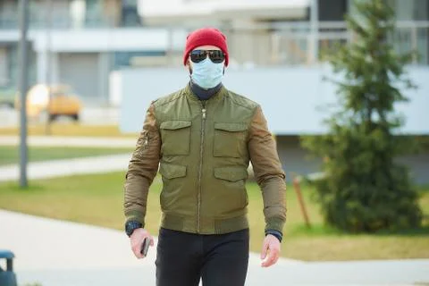 A man in a face mask to avoid the spread coronavirus holding a smartphone Stock Photos