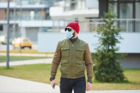 A man in a face mask to avoid the spread coronavirus holding a smartphone Stock Photos