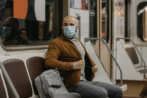 Man in a face mask to avoid the spread of coronavirus is riding in a subway c Stock Photos