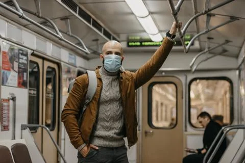 Man in a face mask to avoid the spread of coronavirus is riding in a subway c Stock Photos