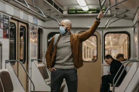 Man in a face mask to avoid the spread of coronavirus is riding in a subway c Stock Photos