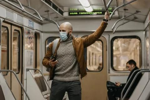 Man in face mask to avoid the spread of coronavirus is using phone in subway  Stock Photos