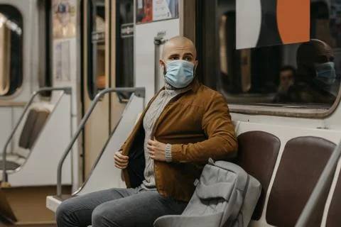Man in a face mask to avoid the spread of coronavirus is riding in a subway c Stock Photos